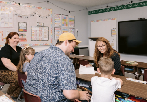 Nancy Bostock visiting a classroom with a teacher and students